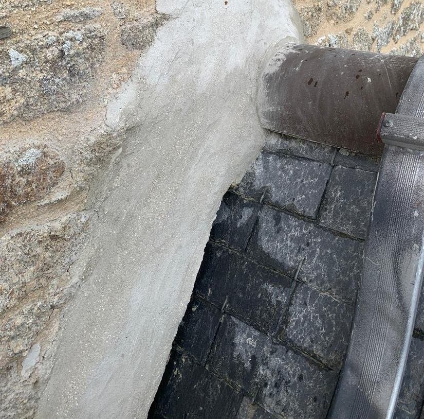 Solin au mortier refait entre un mur en pierre et une toiture en ardoise
